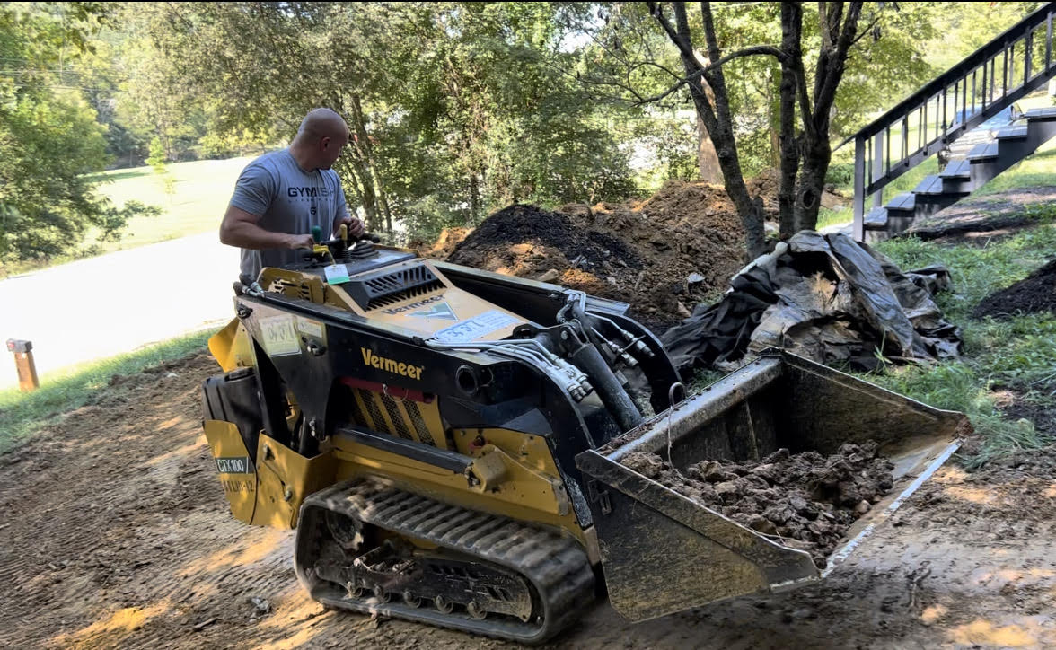 Jamie Trusa operating a walk-behind mini skid steer on a job site